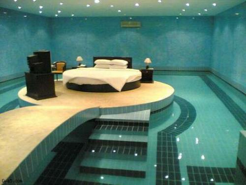 pool bedroom, bedroom with a pool inside of it, bed surrounded by a pool